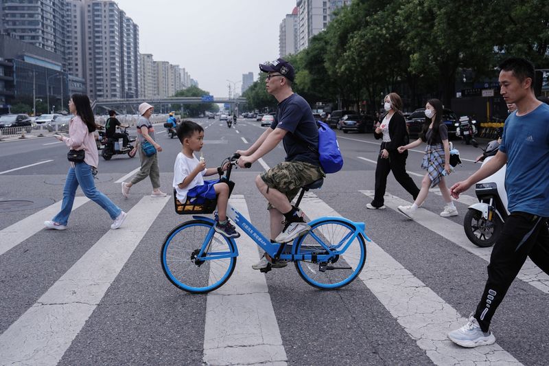 © Reuters. FILE PHOTO: A person rides a bicycle with a child sitting in the basket in Beijing, China July 14, 2024. REUTERS/Tingshu Wang/File Photo