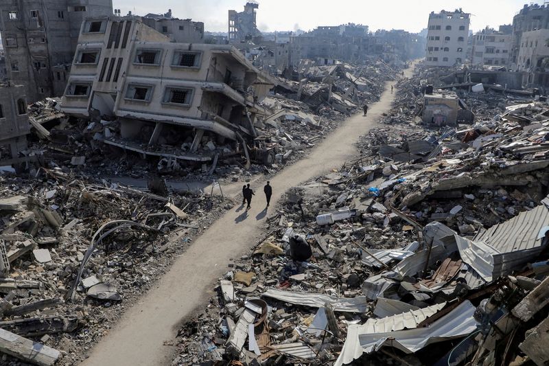 © Reuters. FILE PHOTO: Palestinians walk past destroyed houses, amid the ongoing conflict between Israel and Hamas, in Jabalia refugee camp, in the northern Gaza Strip February 22, 2024. REUTERS/Mahmoud Issa/File Photo