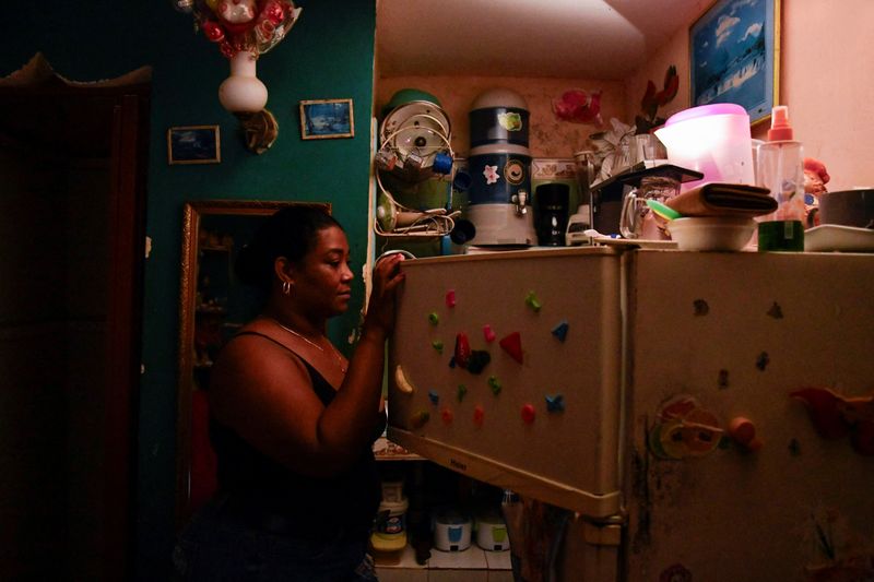 © Reuters. Ramona Miranda opens a refrigerator with the aid of a cell phone light as Cuba is hit by an island-wide blackout, in Havana, Cuba, October 18, 2024. REUTERS/Norlys Perez