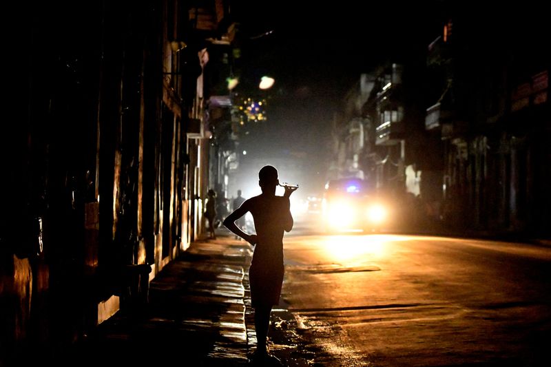 © Reuters. People stand in the street at night as Cuba is hit by an island-wide blackout, in Havana, Cuba, October 18, 2024. REUTERS/Norlys Perez