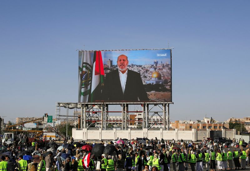 © Reuters. FILE PHOTO: Protesters, mainly Houthi supporters, stand near a screen displaying Senior Hamas official Khalil al-Hayya during a rally to show support to Lebanon's Hezbollah and Palestinians in the Gaza Strip, in Sanaa, Yemen October 18, 2024. REUTERS/Khaled Abdullah/File Photo